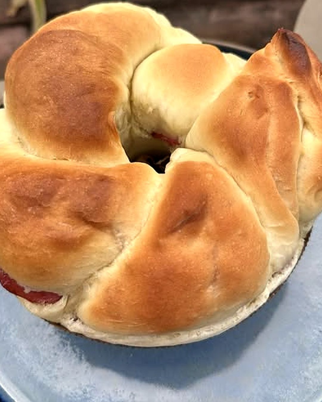 Rosca de calabresa trançada e dourada sobre prato azul